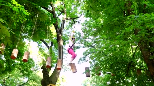 Sisakot és biztonsági berendezések. Koragyermekkori fejlődés. Kid hegymászás fák parkban. Aranyos iskolás kislány élvezi a napsütéses nap egy hegymászó kaland tevékenységi Park. — Stock videók