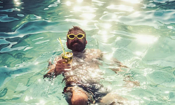 Junger gutaussehender Mann mit moderner Sonnenbrille trinkt Mojito am Strand. — Stockfoto