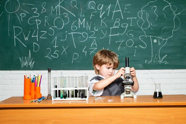 Kid is learning in class on background of blackboard. What is taught in chemistry. Back to school and home schooling. A chemistry demonstration. — Stock Photo, Image