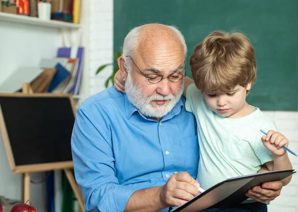 Lern- und Bildungskonzept - Generation People Konzept. Porträt von Großvater und Enkel auf einer Tafel im Klassenzimmer. Grundschule und Bildung. — Stockfoto
