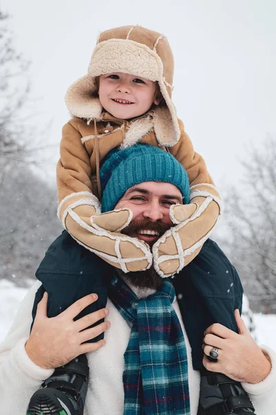 Roztomilá synka ho na zimních prázdninách hubne. Šťastný otec a syn hrají na zimních vánočních svátcích. Otec, který vozím syna zpátky v parku. — Stock fotografie