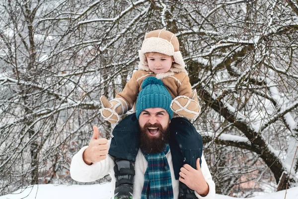 Best winter game for happy family. Father giving son ride on back in park. Happy father and son - winter portrait.