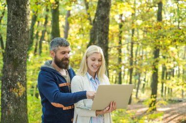 İş çifti - açık havada dizüstü bilgisayarda Internet'te gezinme. Romantik ve aşk. Trendy vintage pullover veya kazak yakışıklı sakallı adam ile Kaygısız genç kadın