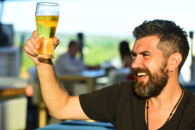 Sakallı adam bira içer. Elinde bira tutan adam. Bar tezgahındaki adam. Hipster barda diniyor. Yakışıklı sakallı adam bira içiyor.