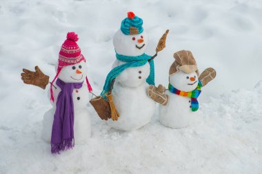 Mutlu Noeller ve kopya alanı ile mutlu yeni yıl tebrik kartı. Karlı alanda şık şapka ve eşarp komik kardan adam aile.
