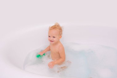 Sevimli küçük çocuk banyoda banyo yaparken gülümsüyor. Mutlu çocukluk. Banyo yaptıran çocuk.