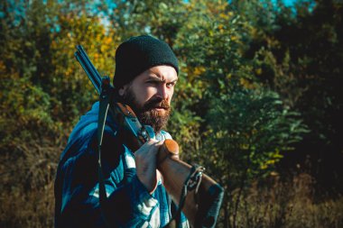 Silah tutan ve ormanda yürüyüş sakallı avcı adam. Hunter avı av tüfeği silah ile.