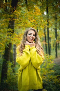 Trendy vintage kırmızı pullover veya kazak tasasız genç kadın. Güneşli sonbahar gününde parkta mutlu genç kadın. Sonbahar kadını parkta eğleniyor ve gülümsüyor. Sonbahar Parkı. Sıcak güneşli hava.