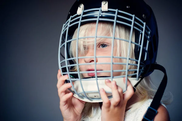 女の子かわいい子供はホッケーのヘルメットをクローズアップ着用します。安全と保護。顔に保護グリッド。スポーツ用品。ホッケーやラグビーのヘルメット。スポーツの子供時代。未来のスポーツスタースポーツ育成とキャリア — ストック写真