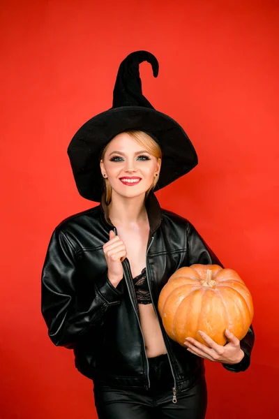 楽しいハロウィンをお過ごし下さい。赤い背景の上にパーティーに黒い魔女ハロウィーンの衣装を着た若い女性. — ストック写真