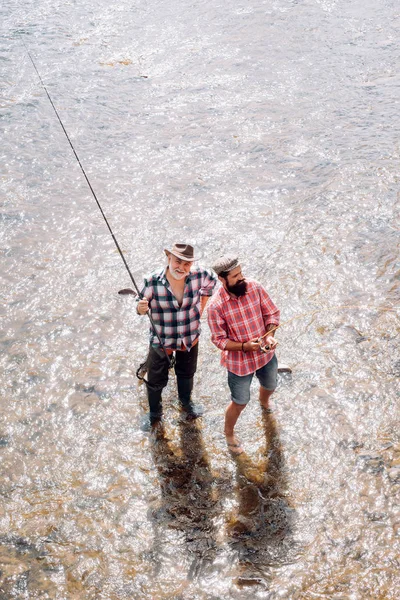 Vader en zoon vissen. Vliegvissen is het meest bekend als een methode voor het vangen van forel en zalm. Visser vissen in een rivier met een hengel. Vissers. — Stockfoto