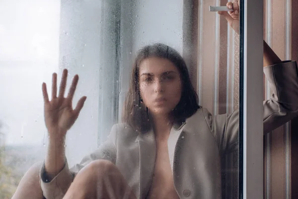 Giovane donna depressa vicino alla finestra a casa, primo piano. Tristezza e delusione . — Foto Stock