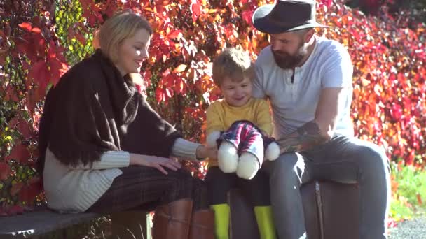 Felice sorridente genitori giovani con il piccolo figlio posa in foglie autunnali. Famiglia d'autunno. Genitorialità familiare e concetto di persone - padre madre felice e bambino nel parco autunnale . — Video Stock