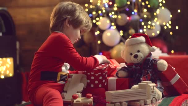 メリークリスマスと新年おめでとうクリスマスのお祝いの休日。クリスマスの飾り贈り物を楽しんで子供をモデル。クリスマスツリーの近くにかわいい子供. — ストック動画