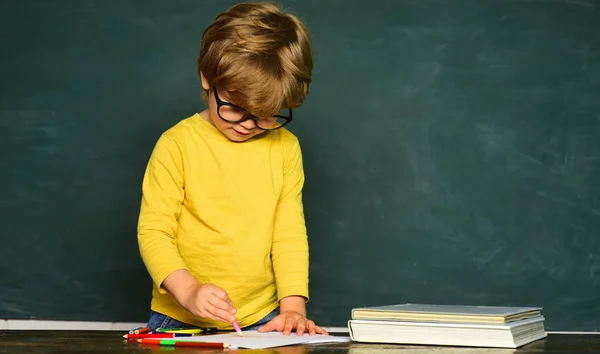 Bambini della scuola. I bambini si preparano per la scuola. Spazio di copia lavagna. Divertente ragazzino che punta sulla lavagna . — Foto Stock