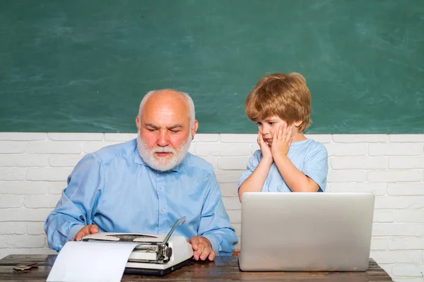 Menino da escola primária e professor com laptop em sala de aula na escola. O pai e o filho juntos. Professor e estudante usando computador em sala de aula sobre quadro-negro . — Fotografia de Stock