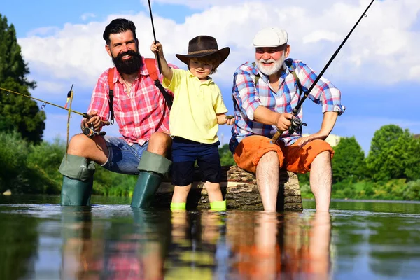 Generazioni uomini. Uomo con il figlio e il padre sulla pesca fluviale con canne da pesca. Nonno e nipote sono pesca a mosca sul fiume . — Foto Stock