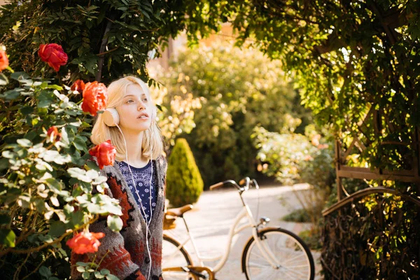Active girl with headphones. Favorite music. Woman headphones blooming garden. Weekend activity. Active leisure and lifestyle. Girl listen music and ride bicycle. Blonde enjoy music in park or garden