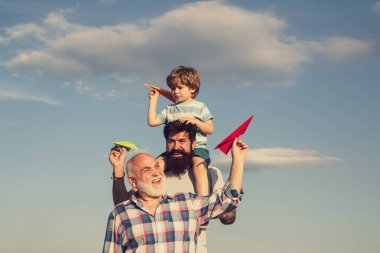 Babalar günü-Büyükbaba, baba ve oğul sarılmak ve birlikte eğlenmek. Uçak uçmaya hazır. Onun omuzlarında oğul piggyback binmek veren ve yukarı bakarak mutlu baba portresi.