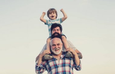 Heyecanlı. Baba ve oğul açık havada oynuyor. Omuz baba kamera bakıyor mutlu gülümseyen çocuk. Mutlu bir aile. Üç erkek nesil.