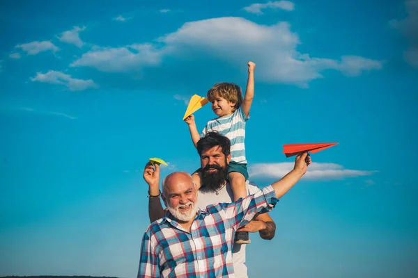 Porträt eines glücklichen Vaters, der seinem Sohn Huckepack auf den Schultern gibt und aufblickt. Traum vom Fliegen. Vatertagskonzept. Generationenkonzept. — Stockfoto