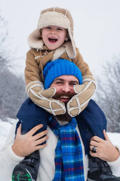 Otec a chlapec se usmívají a jsou v objetí. Vánoční svátky a zimní nový rok s otcem a synem. Zimní scéna na pozadí bílého sněhu. — Stock fotografie