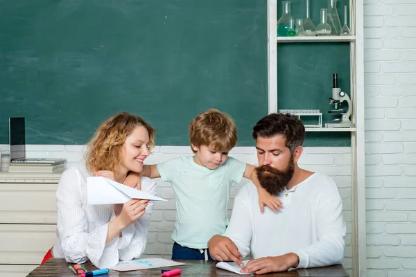 Śmieszne małe dziecko z rodziną bawią się na tle tablicy. Matka ojciec i syn razem szkołowanie. Modele partnerskich społeczności szkolnych. — Zdjęcie stockowe