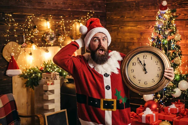 Χριστουγεννιάτικο ρολόι. Ο μουσάτος σύγχρονος Αϊ Βασίλης με πλεκτό πουλόβερ. Η ιδέα του νέου έτους. Αστείος Αϊ-Βασίλης. Όμορφος άντρας φορώντας χριστουγεννιάτικο φόρεμα. — Φωτογραφία Αρχείου