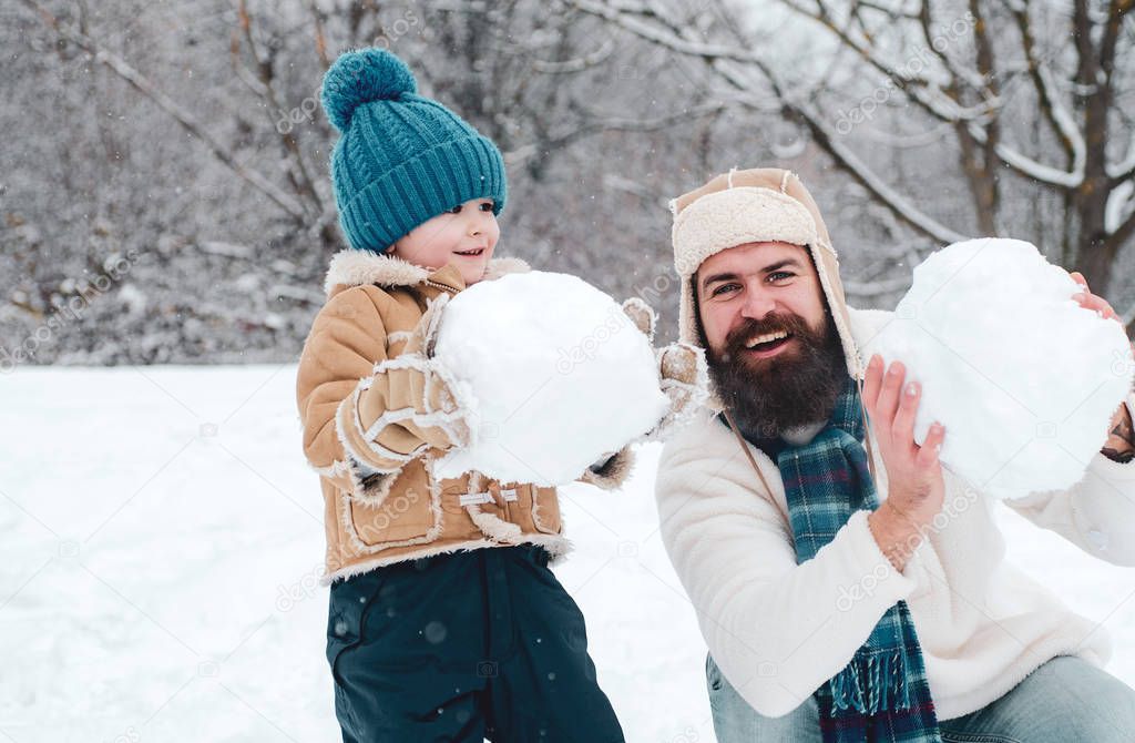 Happy father and son making snowman in the snow. Winter family in frosty winter Park. Winter father and son. Merry Christmas and Happy new year.