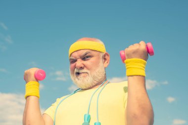 Mavi gökyüzü arka planda kaldırma dumbbell ile egzersiz komik kıdemli ögrenci. Yalıtılmış, kopya alanı.
