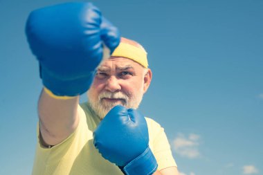 Savaşçı. Boks eldivenleri olan boksör. Eldivenli kıdemli adam yumruk torbası atıyor. Boks. Yaşlı adam boks. Boks severim. Kıdemli havalı adam mücadele.