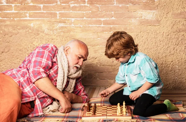 Grand-père et petit-fils jouant aux échecs. Grand-père et petit-fils jouent aux échecs et sourient tout en passant du temps ensemble à la maison. Chessman ! . — Photo