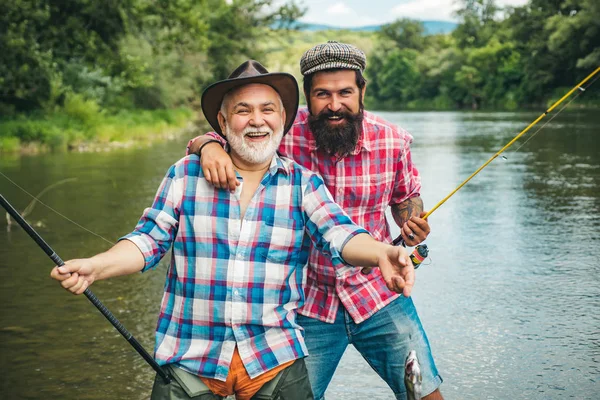 Unterschied zwischen Fliegenfischen und regulärem Fischen. glücklicher Vater und Sohn beim gemeinsamen Angeln an einem Sommertag unter schönem Himmel am Fluss. — Stockfoto