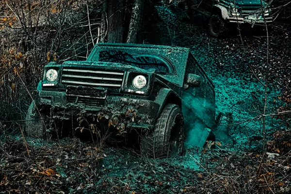 越野车从泥孔危险中驶出。吉普车撞到水坑里,捡起一喷的泥土。越野旅行在山路上。越野车上山. — 图库照片