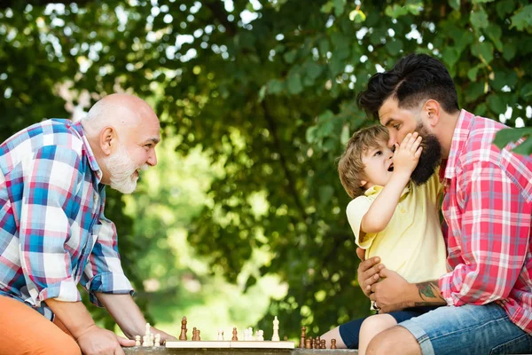 Nonno e nipote che giocano a scacchi. Generazione familiare: sogno futuro e concetto di persone. Nonno dell'età dell'oro. Padre e figlio giocare a scacchi con il nonno all'aperto . — Foto Stock