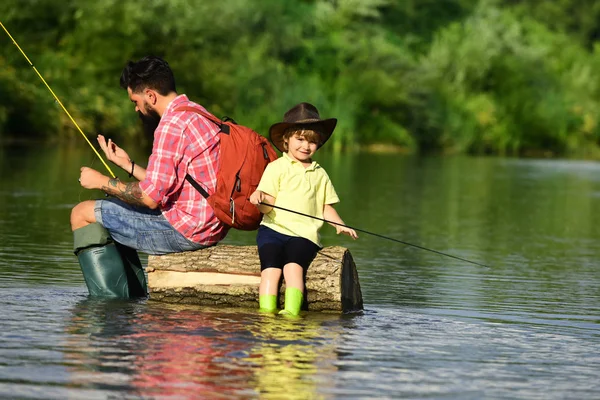 Felice Padre e Figlio insieme pesca nel giorno d'estate sotto il bel cielo sul fiume. Pesca nel fiume. Ragazzino pesca con il padre . — Foto Stock