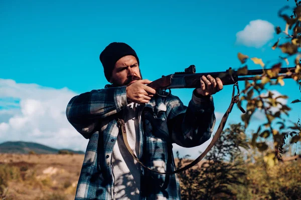 Un chasseur barbu tenant une arme et marchant dans la forêt. Chasseur avec fusil de chasse en chasse. Grand jeu . — Photo