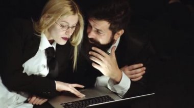 Dizüstü bilgisayar kullanarak iş çift. İş adamı izole-yakışıklı adam ve siyah arka planda güzel kadın. İş yeri romantizm numarası. Yazma iletisi yazılır. Sosyal medya.