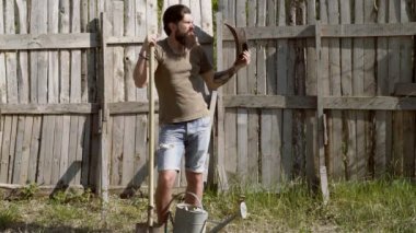 Hipster çiftçi doğa arka planda rahatlatıcı. Bir çiftlikte eğlenmek kürek ile sakallı adam çiftçi tam vücut portre. Bahçe aletleri. İnsan yere dikiyor. Ülke yaşamı.
