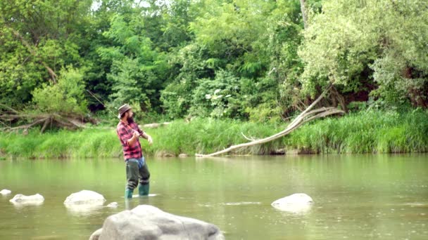 A pescar. Pescador bonito pescando em um rio com uma vara de pesca. Homem pescador pega um peixe. Peixe e conceito de pesca. Vara de mosca e movimento cambaleante com uma truta marrom de uma corrente . — Vídeo de Stock