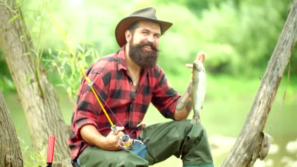 Trucha. Pescador guapo pescando en un río con una caña de pescar. Trucha arco iris Steelhead. Retrato de hombre alegre pescando. Pesca . — Vídeo de stock