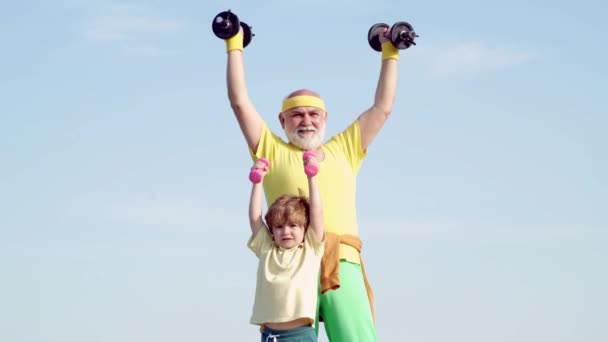 Abuelo y nieto con sombrillas en las manos. Los niños repiten el ejercicio después del abuelo. Vida familiar saludable. Deporte familiar . — Vídeos de Stock