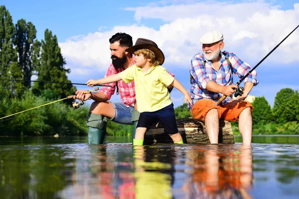 La pesca divenne un'attività ricreativa popolare. Nonno con figlio e nipote che si divertono nel fiume. Un hobby maschile. Pescatori familiari che pescano con mulinello . — Foto Stock