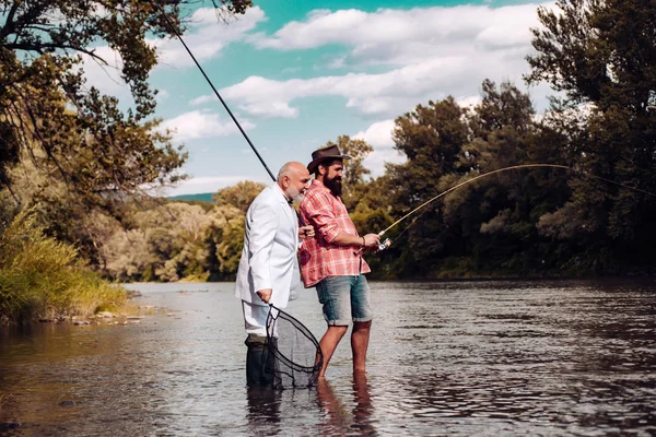 Dönen makaralı balıkçı lar. Baba ve oğul balık tutuyor. Genç adam ve yaşlı olgun adam balık avlamak. Nehirde olta ile Balıkçılar. — Stok fotoğraf