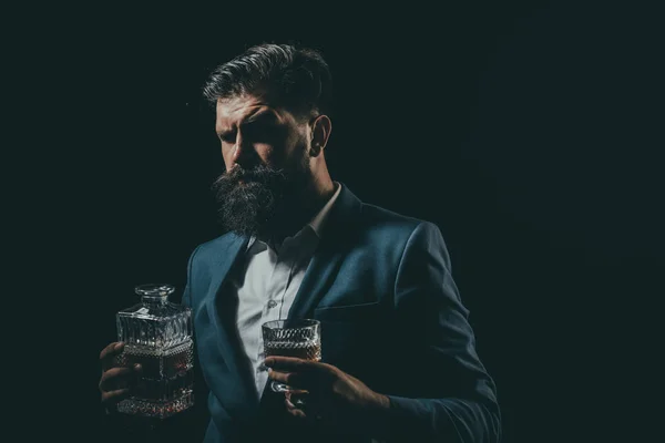 Atractivo camarero en el bar de whiskey. Elegante hombre rico sosteniendo un vaso de whisky viejo. Hombre con barba sostiene brandy de vidrio . — Foto de Stock