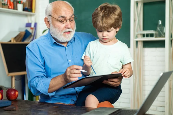 Lehrer ist kompetenter Führer. Großvater und Enkel lernen zusammen. lustiges kleines Kind, das Spaß an der Tafel hat. Bildungskonzept für Schüler und Nachhilfe. — Stockfoto