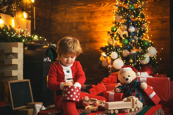 Семейный праздник. Детские воспоминания. Мальчик Санта празднует Рождество дома. Мальчик играет возле рождественской елки. Счастливого и светлого Рождества. Детство и игры. Любимая детская забава — стоковое фото