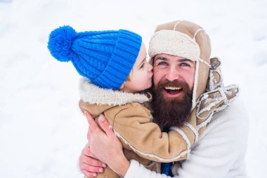 Mutlu aile oğlu kış tatilinde babasına sarılır. Baba ve çocuk gülümsüyor ve sarılıyorlar. Mutlu Noeller ve Mutlu Yıllar. Noel'den önceki sabah. Mutlu baba ve oğul - kış portresi.