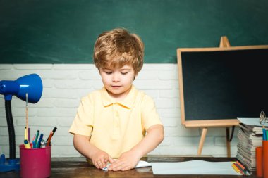 İlkokul ve eğitim - okul kavramı. Kitaplı çocuk. Komik küçük çocuk tahta arka plan üzerinde eğleniyor. Okul konsepti. Kitap ile Mutlu sevimli akıllı çocuk öğrenci.