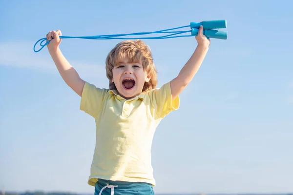 青空の背景にジャンプロープで運動するかわいい少年の肖像画。晴れた朝の間にロープをスキップする子供. — ストック写真